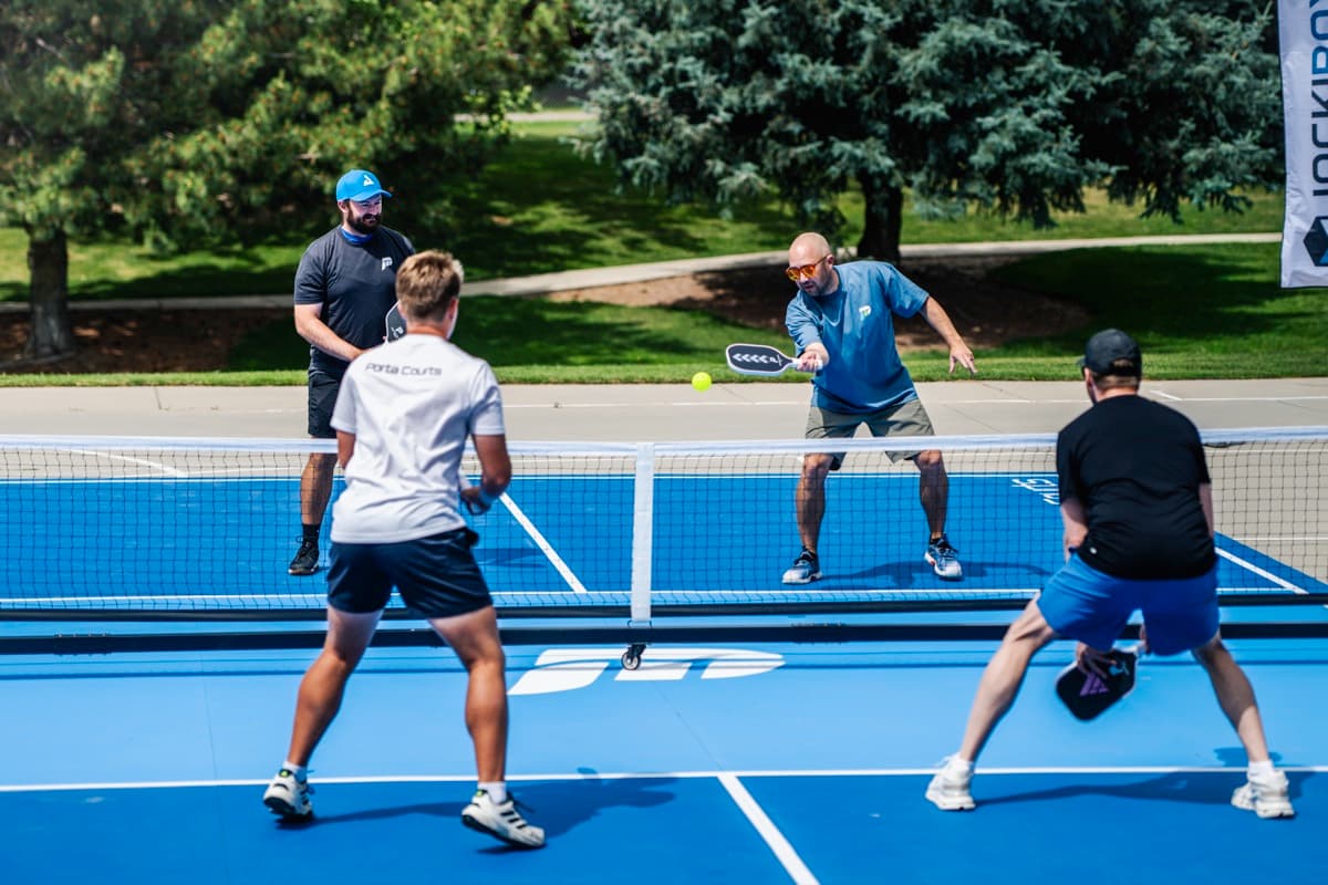 Doubles pickleball action on a blue PortaCourt